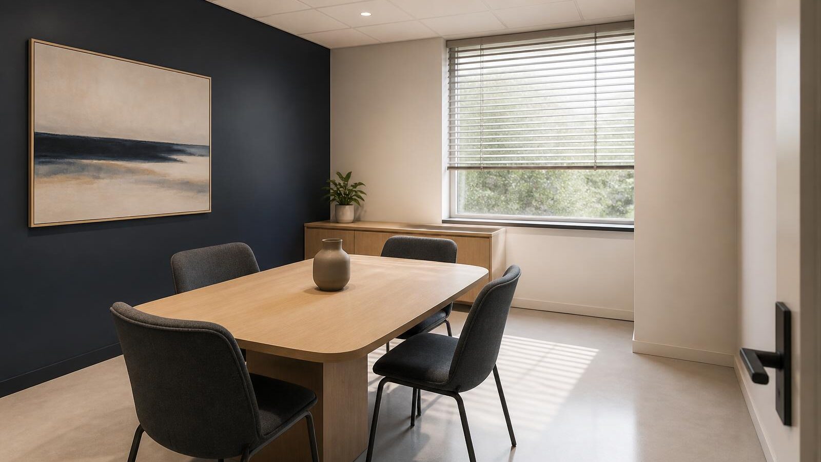 Small professional meeting room with clear surfaces, wiped table, and light flooring